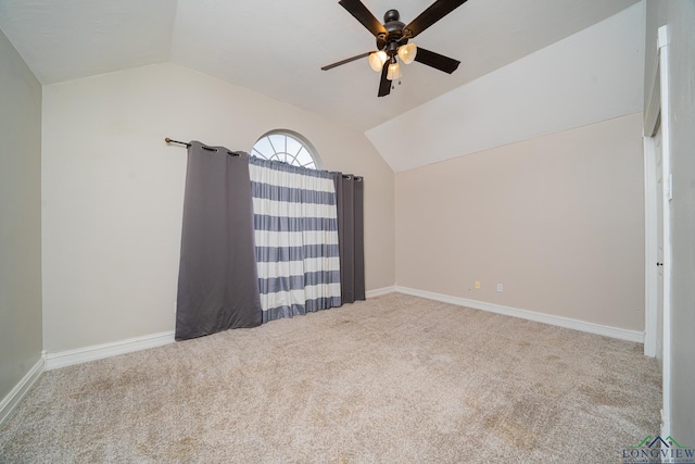 carpeted spare room with ceiling fan and vaulted ceiling