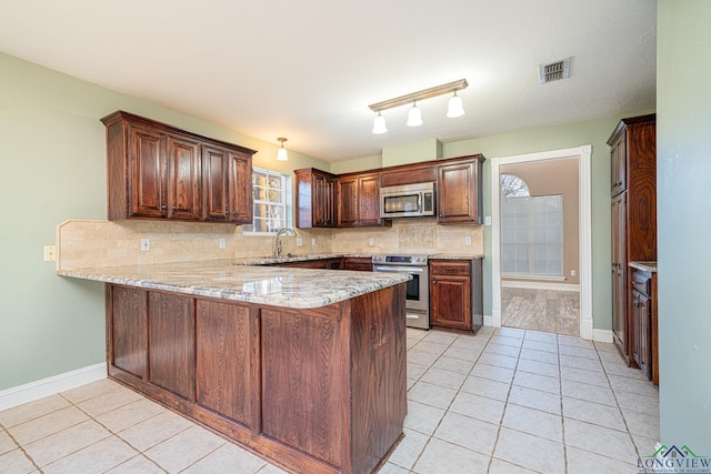 kitchen featuring light tile patterned flooring, kitchen peninsula, stainless steel appliances, and tasteful backsplash