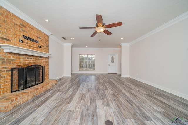 unfurnished living room with a brick fireplace, hardwood / wood-style floors, crown molding, and ceiling fan