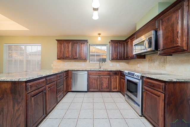 kitchen with kitchen peninsula, appliances with stainless steel finishes, tasteful backsplash, light tile patterned floors, and light stone counters