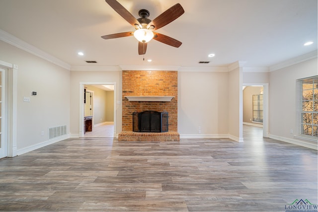 unfurnished living room featuring ceiling fan, wood-type flooring, ornamental molding, and a fireplace