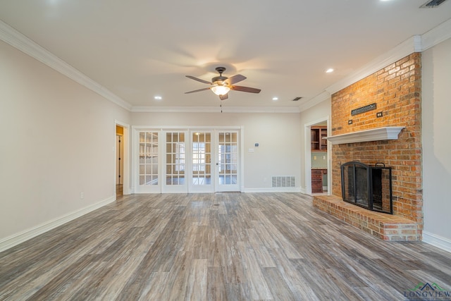 unfurnished living room featuring hardwood / wood-style flooring, french doors, ornamental molding, and a fireplace