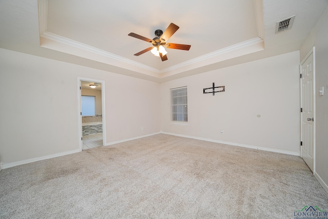 empty room with ceiling fan, light colored carpet, and a raised ceiling