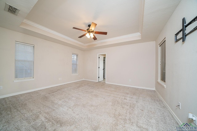 carpeted spare room featuring ceiling fan, ornamental molding, and a tray ceiling