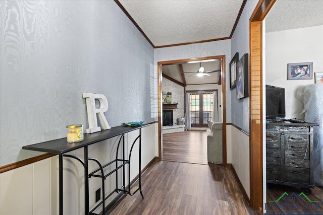 hallway with a textured ceiling, ornamental molding, and dark wood-type flooring