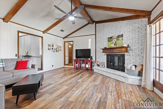 living area with a brick fireplace, visible vents, a textured ceiling, and wood finished floors