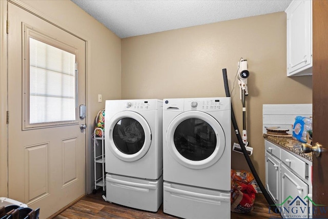 laundry room with a textured ceiling, dark wood-style flooring, washing machine and dryer, and cabinet space