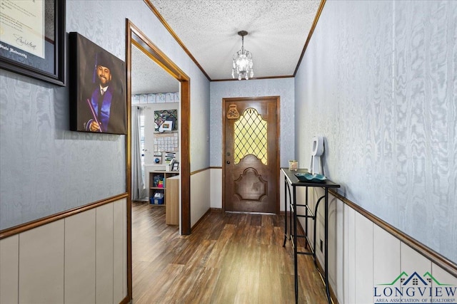 entryway with a textured wall, dark wood-style floors, a textured ceiling, crown molding, and a chandelier