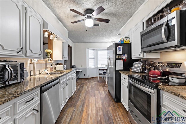 kitchen with dark wood finished floors, white cabinetry, stainless steel appliances, and a sink