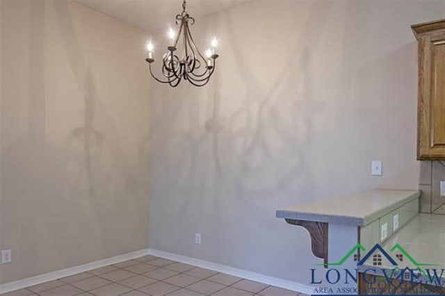 unfurnished dining area with a chandelier, baseboards, and light tile patterned floors