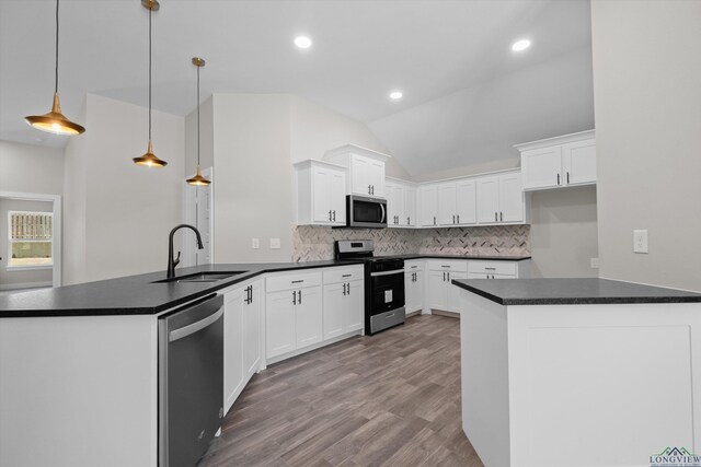 kitchen with white cabinets, stainless steel appliances, sink, hanging light fixtures, and kitchen peninsula