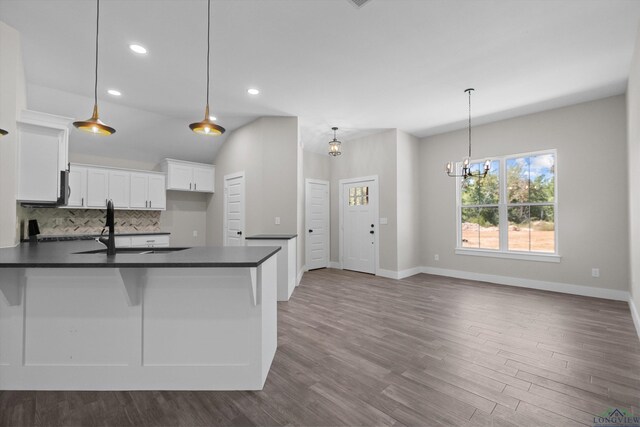 kitchen with sink, white cabinetry, hanging light fixtures, and tasteful backsplash