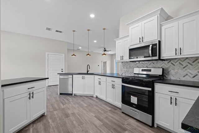 kitchen featuring decorative light fixtures, sink, white cabinetry, and appliances with stainless steel finishes