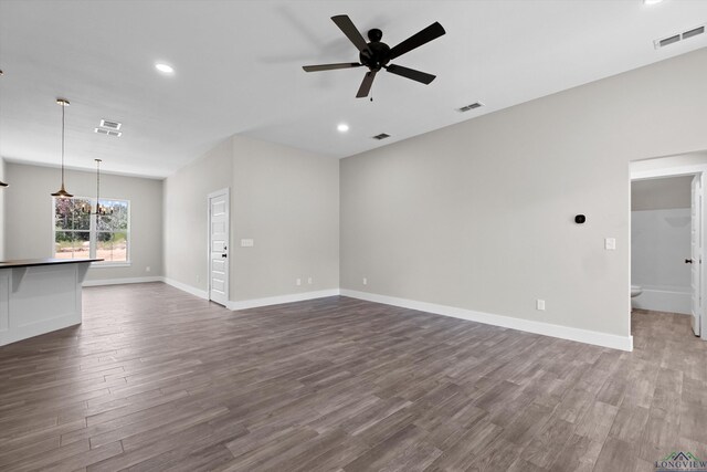 unfurnished living room with ceiling fan with notable chandelier and dark hardwood / wood-style flooring