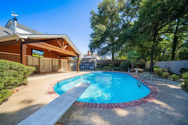 view of pool with a patio area, a diving board, and a shed