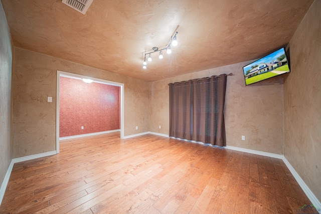 spare room featuring hardwood / wood-style flooring and rail lighting