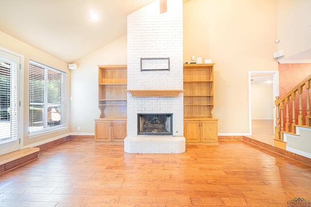 unfurnished living room featuring a brick fireplace, high vaulted ceiling, and light wood-type flooring