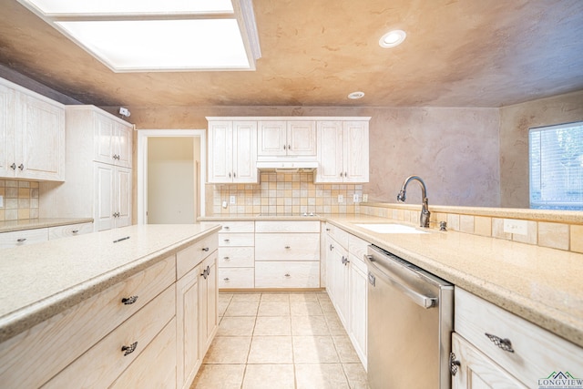 kitchen with light tile patterned floors, tasteful backsplash, stainless steel dishwasher, and sink