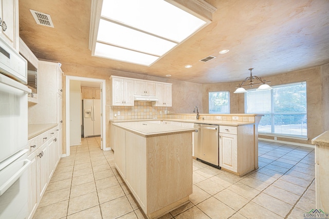 kitchen featuring white fridge with ice dispenser, dishwasher, a center island, decorative light fixtures, and decorative backsplash