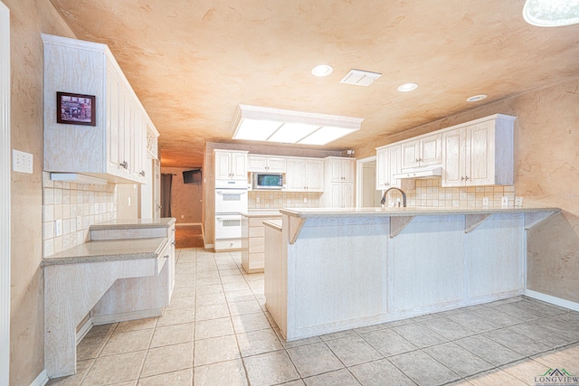 kitchen featuring a kitchen breakfast bar, white cabinetry, and kitchen peninsula