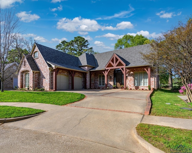 french country home featuring a front yard, brick siding, and a garage