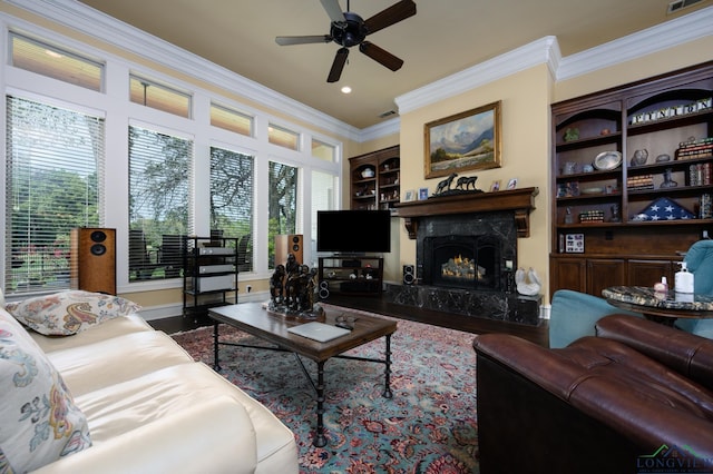 living room with built in features, ornamental molding, a ceiling fan, wood finished floors, and a premium fireplace