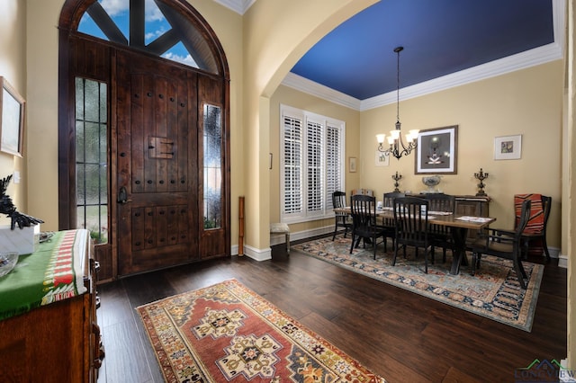 foyer entrance with ornamental molding, arched walkways, a chandelier, and dark wood-style floors