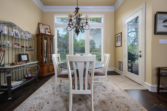 dining space with dark wood-type flooring, an inviting chandelier, and ornamental molding
