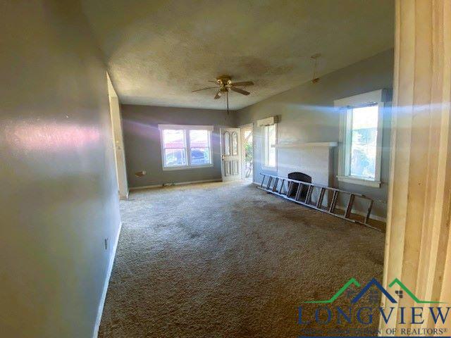 unfurnished living room with ceiling fan, carpet floors, and a textured ceiling