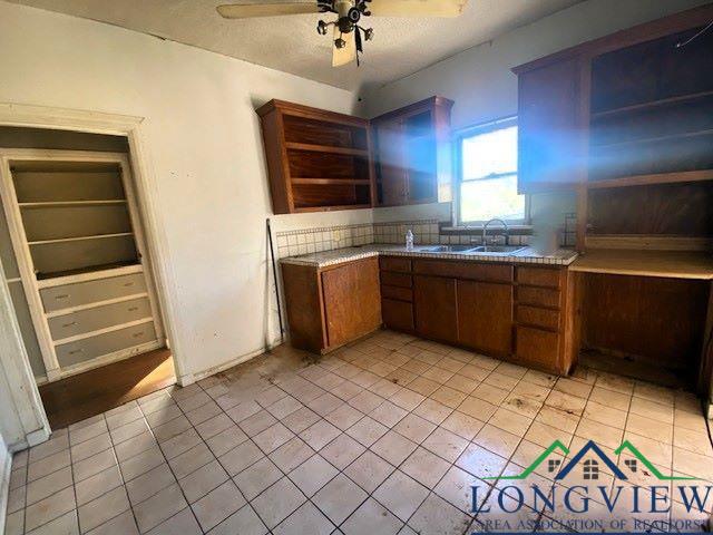 kitchen featuring light tile patterned flooring, ceiling fan, and sink