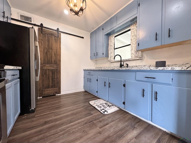 1612 Oden St, Longview, TX 75602 - kitchen featuring dark wood-style floors, freestanding refrigerator, a barn door, baseboards, and blue cabinetry