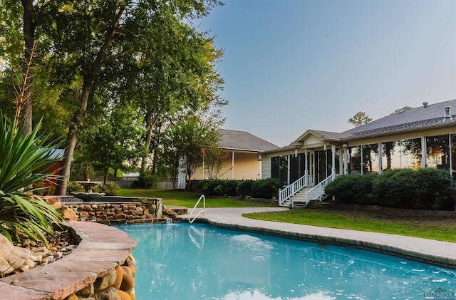 view of pool with a lawn and a sunroom