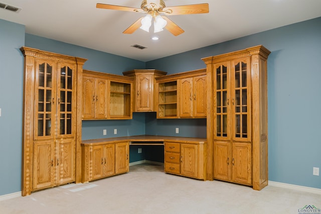 kitchen with ceiling fan, built in desk, and light carpet