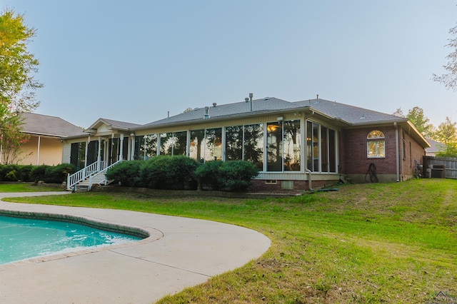 rear view of property with a sunroom and a lawn