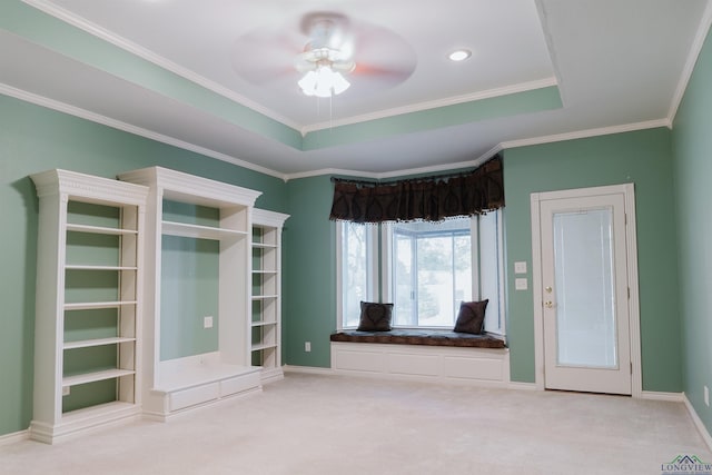 interior space featuring a raised ceiling, ceiling fan, carpet floors, and ornamental molding