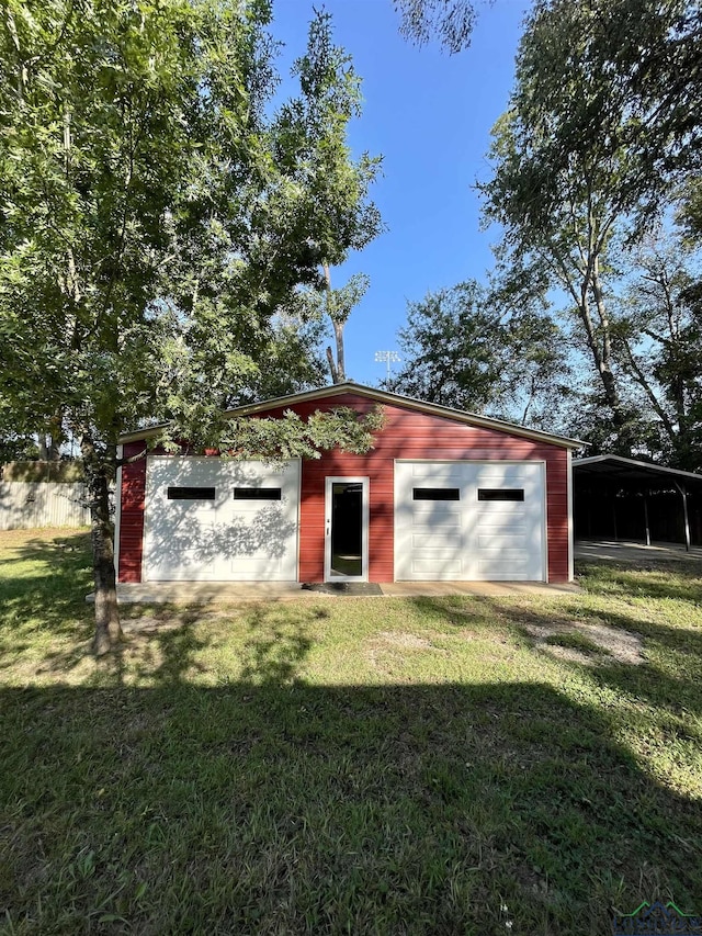 view of outdoor structure featuring a yard, a carport, and a garage