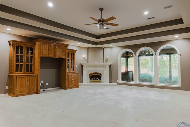 unfurnished living room with light carpet, a raised ceiling, ceiling fan, and crown molding