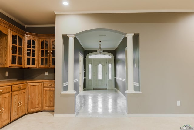 tiled foyer entrance featuring ornamental molding and decorative columns