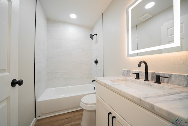 full bathroom featuring hardwood / wood-style flooring, vanity, tiled shower / bath combo, and toilet