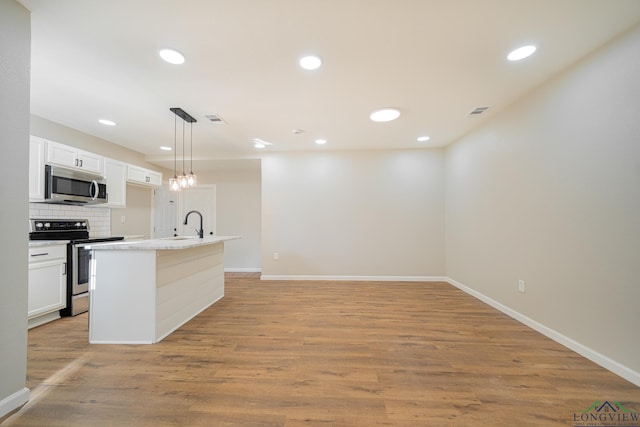 kitchen featuring white cabinetry, appliances with stainless steel finishes, decorative backsplash, and pendant lighting