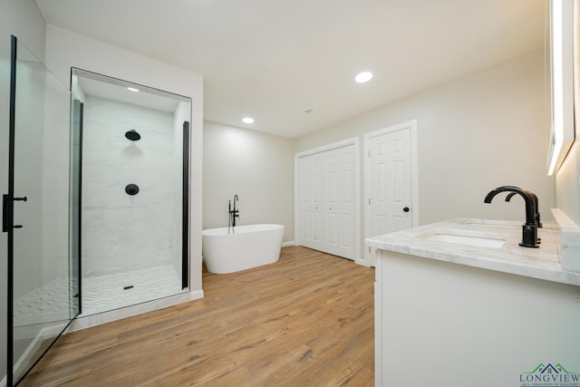 bathroom featuring hardwood / wood-style flooring, vanity, and shower with separate bathtub