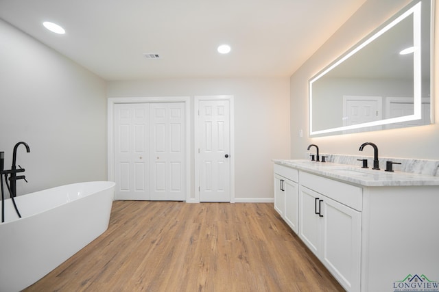 bathroom featuring hardwood / wood-style flooring, vanity, and a washtub