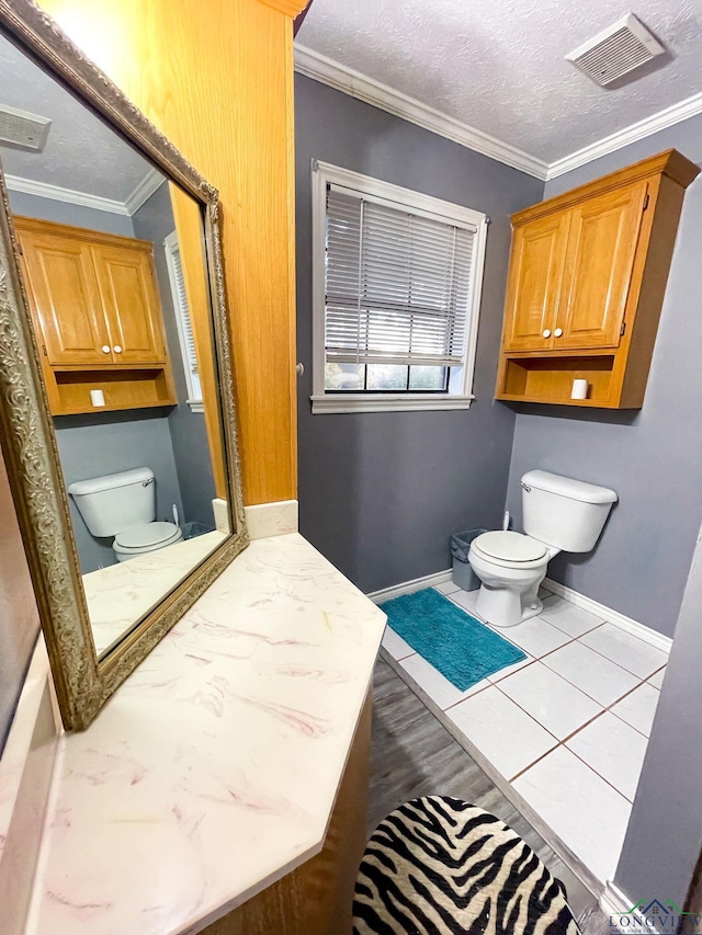 bathroom featuring tile patterned floors, toilet, ornamental molding, and a textured ceiling