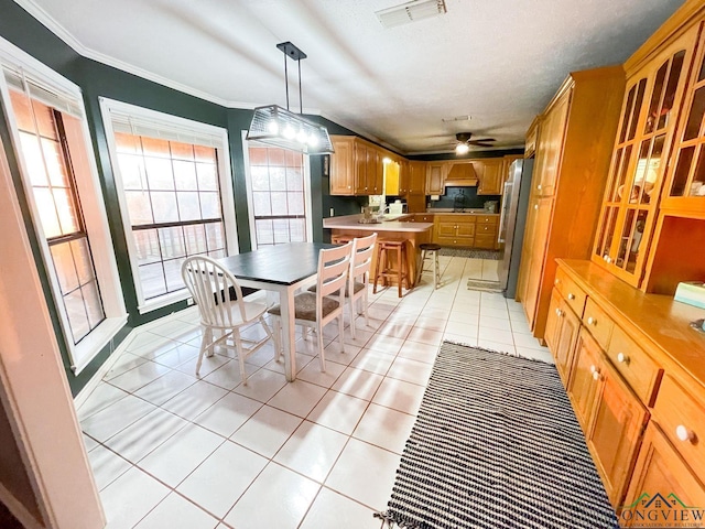 tiled dining room featuring ceiling fan, crown molding, and plenty of natural light