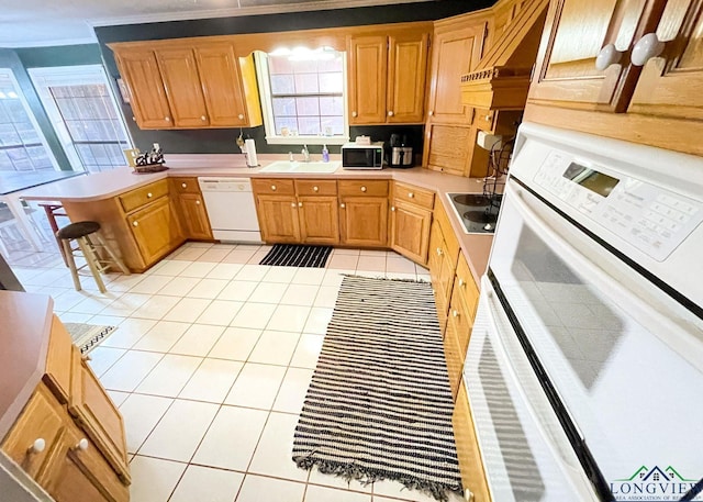 kitchen featuring sink, kitchen peninsula, crown molding, white appliances, and light tile patterned floors