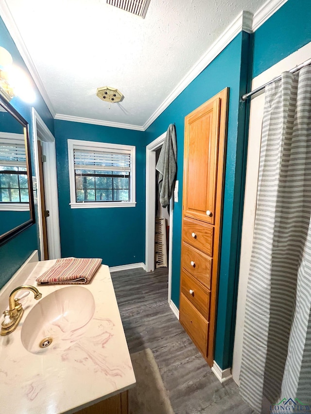 bathroom featuring a textured ceiling, vanity, wood-type flooring, and ornamental molding