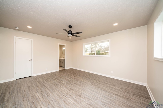 unfurnished room featuring a textured ceiling, baseboards, and wood finished floors