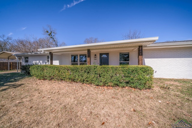 ranch-style home with a carport, brick siding, and a front yard