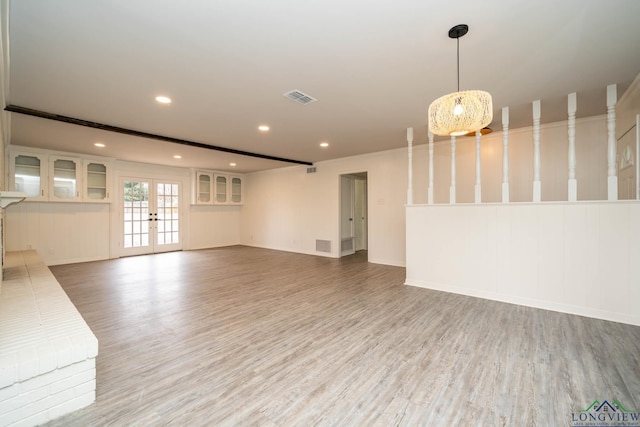 unfurnished living room featuring visible vents, wood finished floors, and french doors