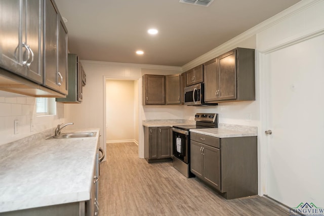 kitchen featuring light wood-type flooring, appliances with stainless steel finishes, light countertops, and a sink